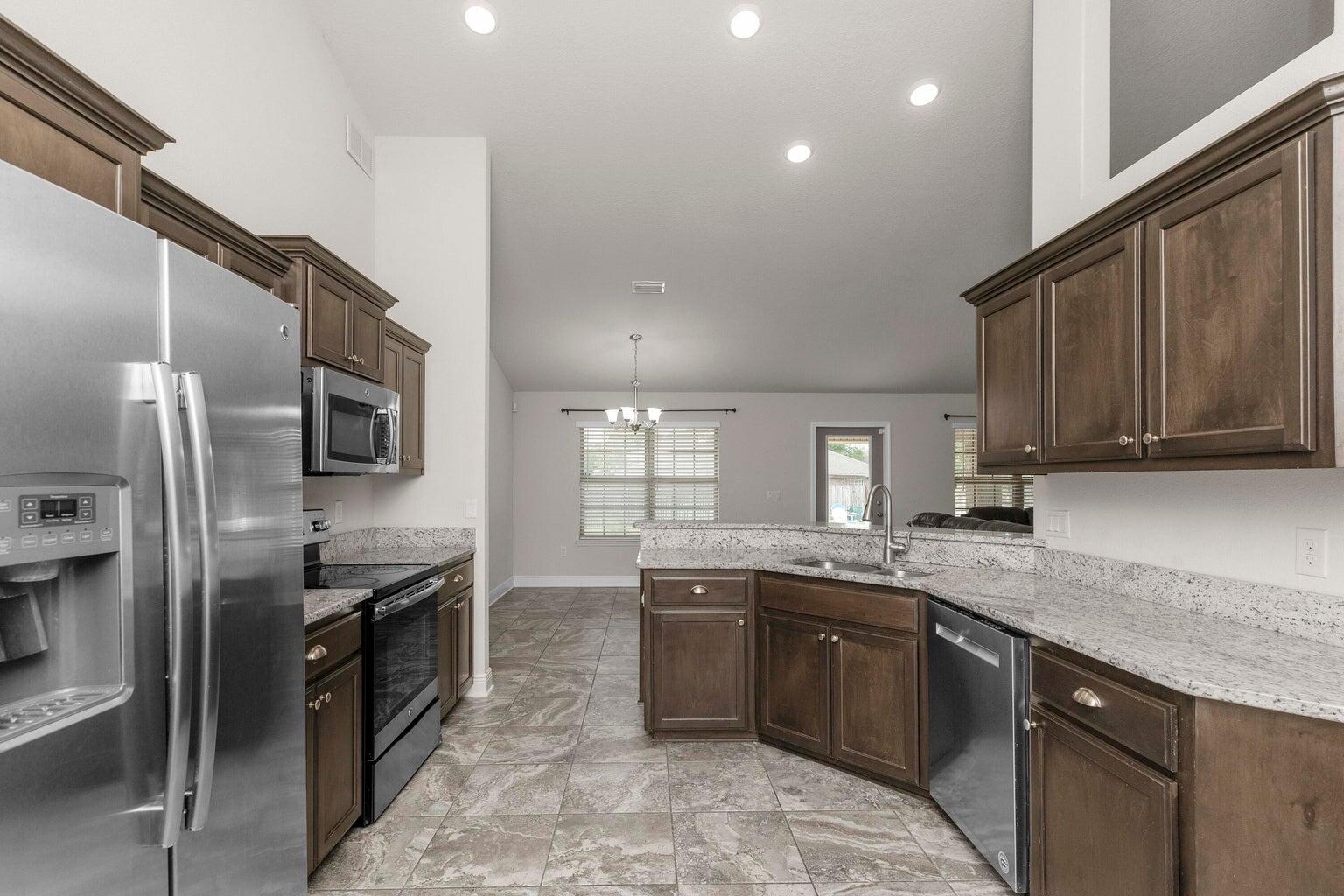 2365 Genevieve Way Crestview, FL 32536 - Photo 8 of 33 a kitchen with stainless steel appliances granite countertop a sink stove and refrigerator