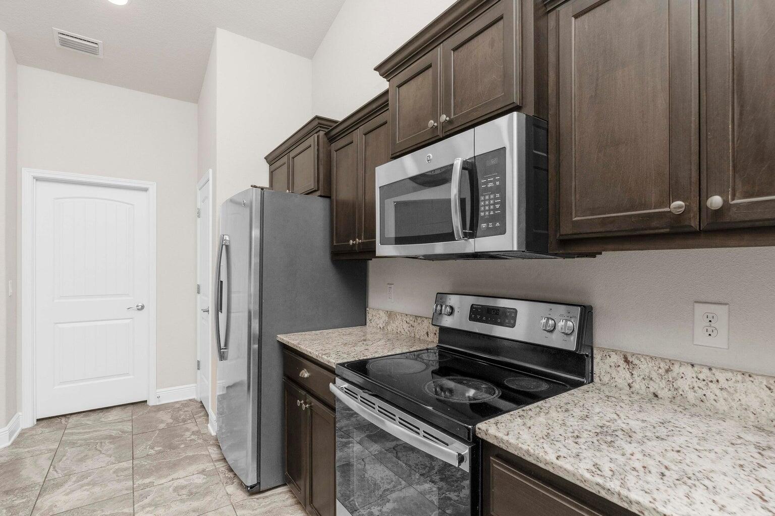 2365 Genevieve Way Crestview, FL 32536 - Photo 9 of 33 a kitchen with stainless steel appliances granite countertop a stove microwave and refrigerator