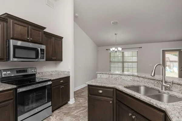 a kitchen with stainless steel appliances granite countertop a sink stove and microwave