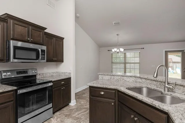 a kitchen with stainless steel appliances granite countertop a sink stove and microwave