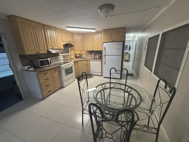 a kitchen with stainless steel appliances a refrigerator a sink a stove a microwave oven with a dining table and chairs