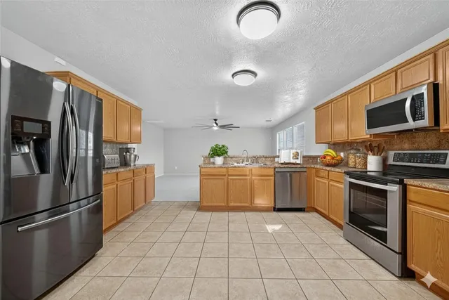 a kitchen with stainless steel appliances granite countertop a refrigerator oven a sink dishwasher and white cabinets with wooden floor