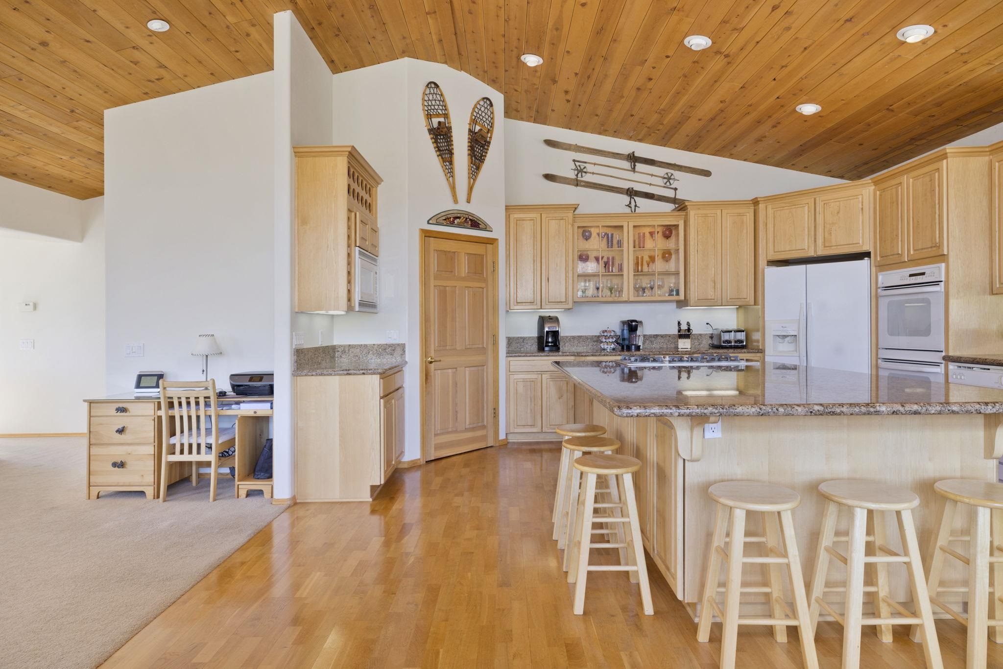 492 John Muir Road Mammoth Lakes, CA 93546 - Photo 5 of 33 Vaulted wood-paneled ceiling, recessed lighting, wood-finish flooring, built-in desk, and a kitchen island with stone countertops