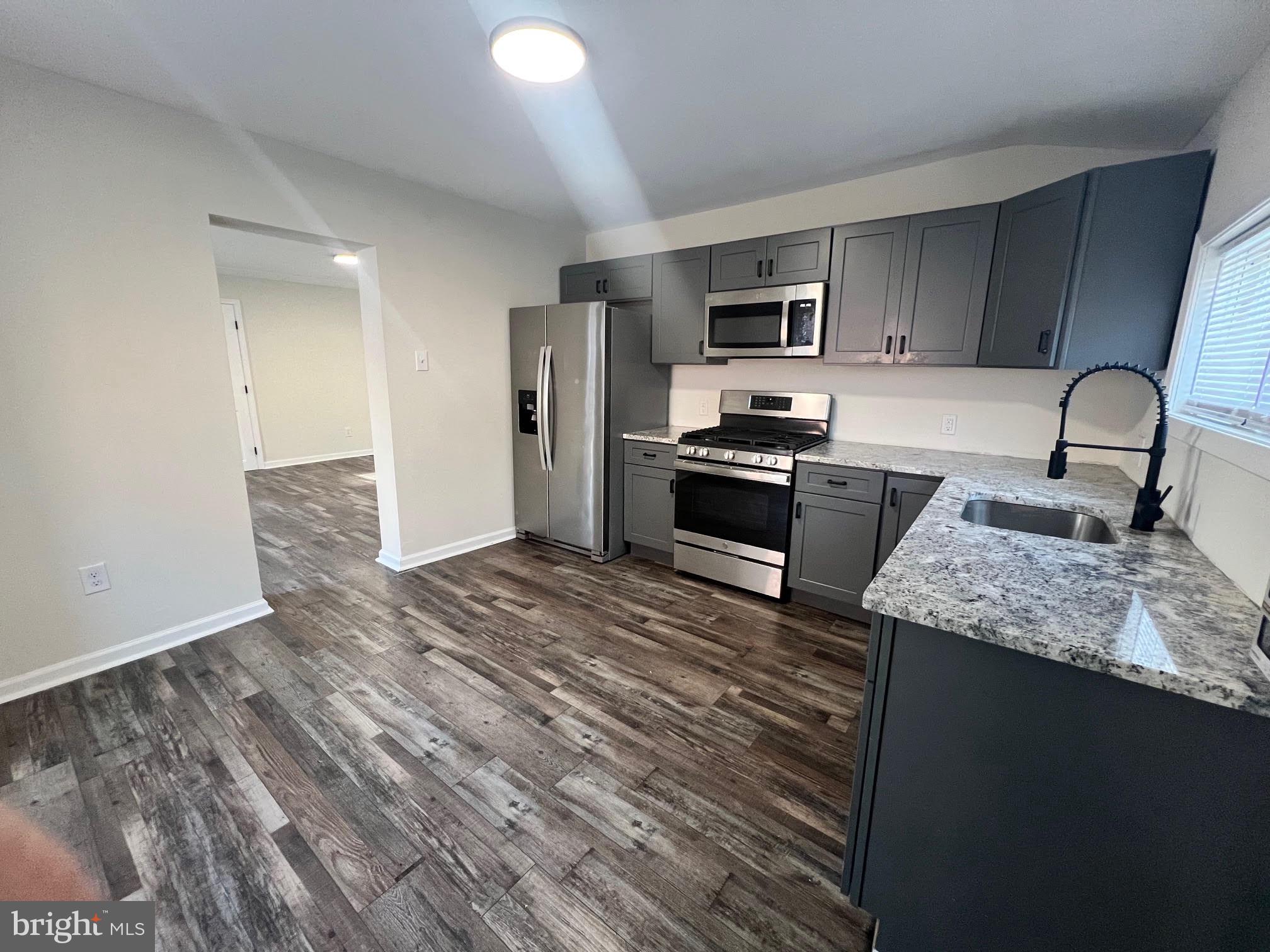 107 Church Street, Unit B Glassboro, NJ 08028 - Photo 4 of 9 a kitchen with stainless steel appliances granite countertop a stove top oven a sink and dishwasher a refrigerator with wooden floor