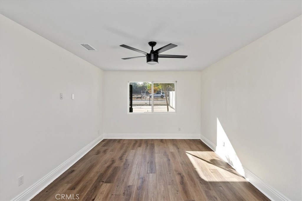 19594 Temescal Canyon Road Corona, CA 92881 - Photo 46 of 50 an empty room with wooden floor ceiling fan and windows