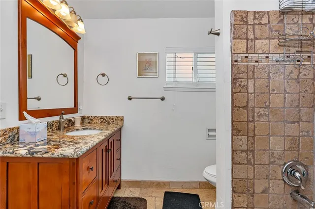 a bathroom with a granite countertop sink toilet and shower