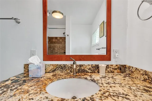 a bathroom with a granite countertop sink and a mirror