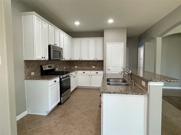 a kitchen with granite countertop a sink stove and cabinets