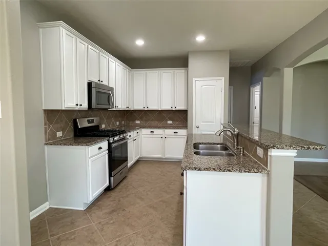 a kitchen with granite countertop a sink stove and cabinets