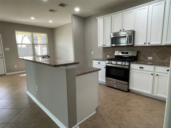 a kitchen with stainless steel appliances granite countertop a sink a stove and a wooden cabinets