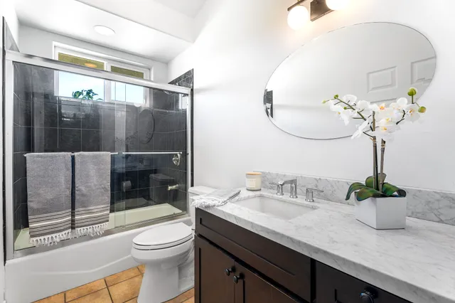 a bathroom with a granite countertop sink a toilet and shower