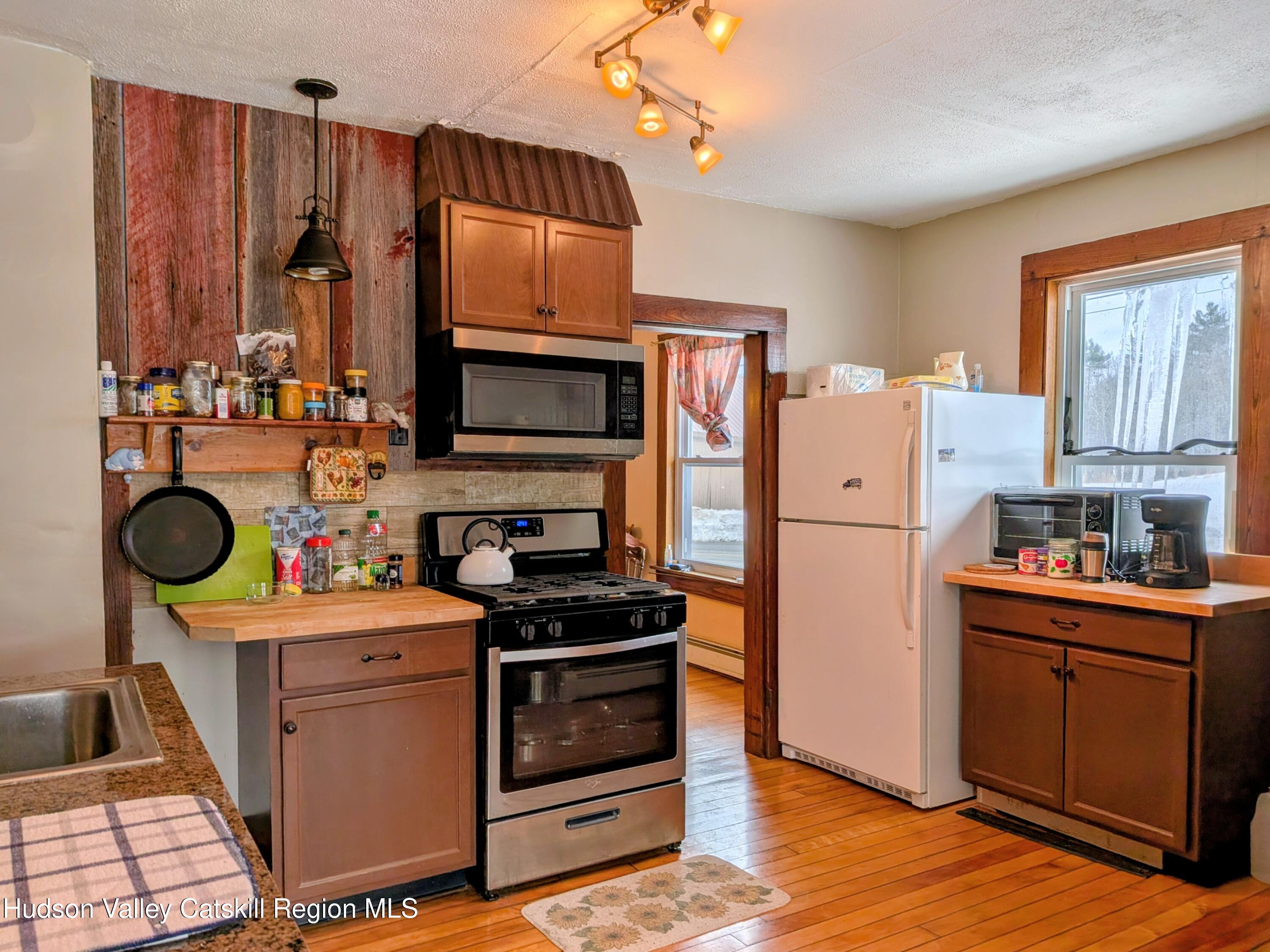 351 Presbyterian Hill Road Stephentown, NY 12168 - Photo 13 of 46 a kitchen with stainless steel appliances a stove top oven a sink dishwasher and a refrigerator with wooden floor