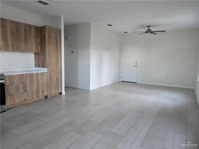 an empty room with wooden floor cabinet and windows