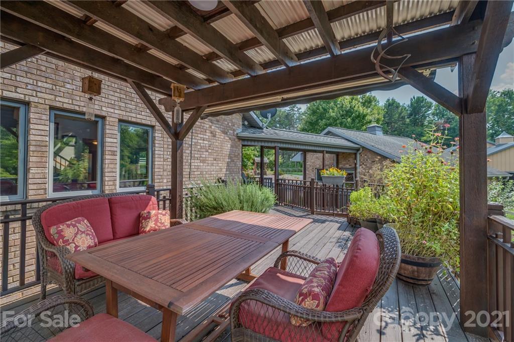 2101 Peniel Road Columbus, NC 28722 - Photo 17 of 48 a view of a patio with table and chairs potted plants with wooden floor and floor to ceiling window