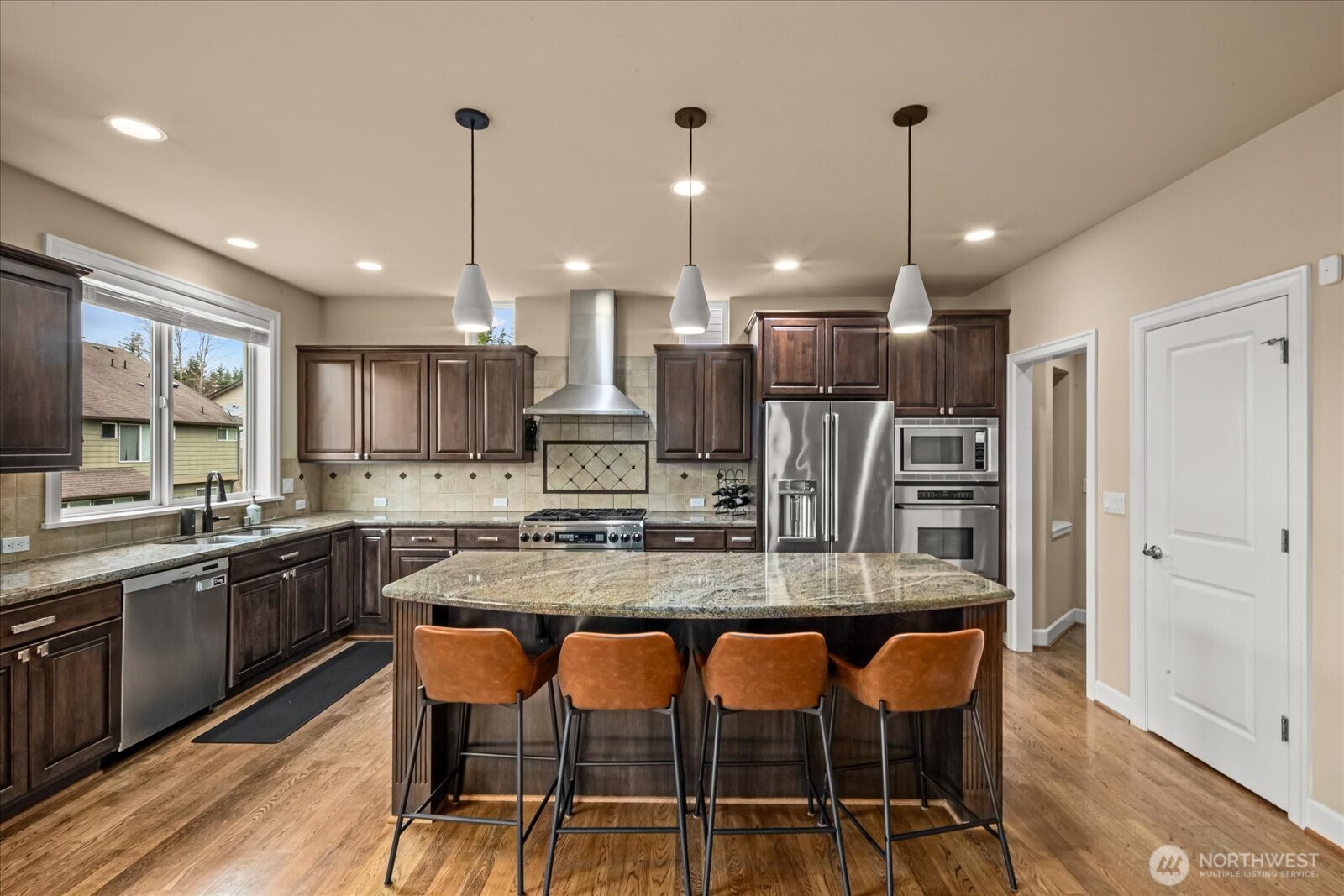 215 Ilwaco Place Southeast Renton, WA 98059 - Photo 15 of 40 a kitchen with stainless steel appliances granite countertop a table chairs sink and stove top oven