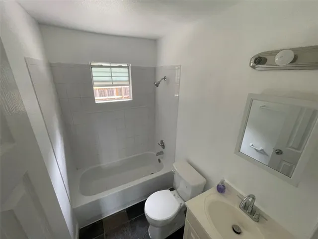 an empty room with wooden floor cabinet and windows