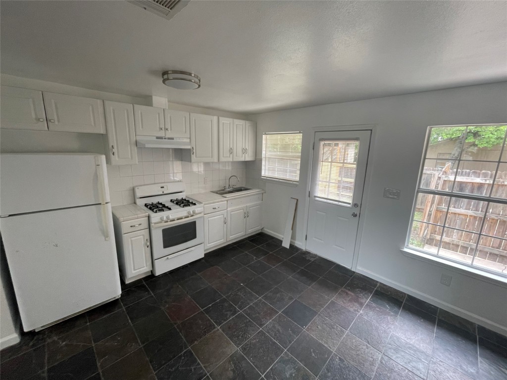 2808 Lyons Road, Unit A Austin, TX 78702 - Photo 3 of 13 a kitchen with granite countertop white cabinets and white appliances