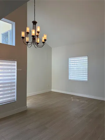 a view of an empty room with wooden floor and windows