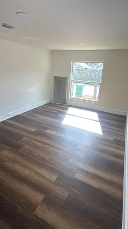 a view of an empty room with a window and wooden floor