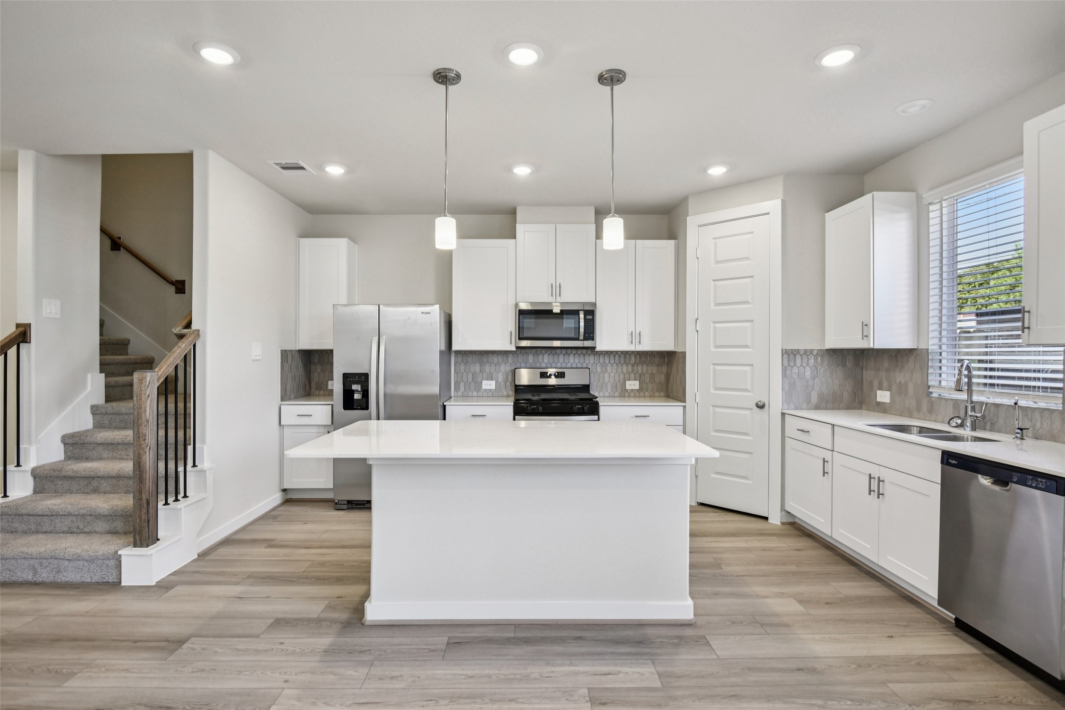 10012 Rustic Charm Street Houston, TX 77080 - Photo 10 of 45 a large kitchen with stainless steel appliances kitchen island granite countertop a stove a sink a refrigerator and white cabinets with wooden floor