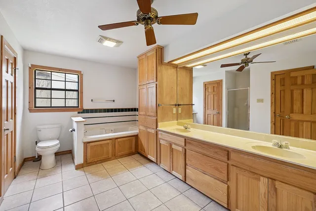 a spacious bathroom with a double vanity sink a mirror and a toilet