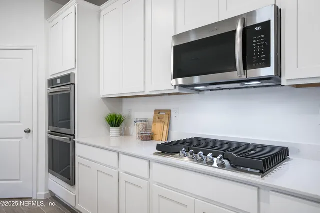 a kitchen with stainless steel appliances kitchen island granite countertop a refrigerator and a dining table with wooden floor