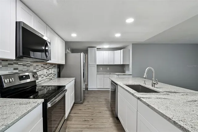 a kitchen with stainless steel appliances granite countertop a refrigerator stove top oven and sink