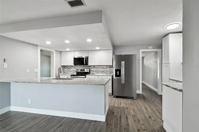 a view of an empty room with wooden floor and a ceiling fan