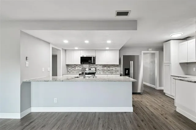 a view of an empty room with wooden floor and a ceiling fan