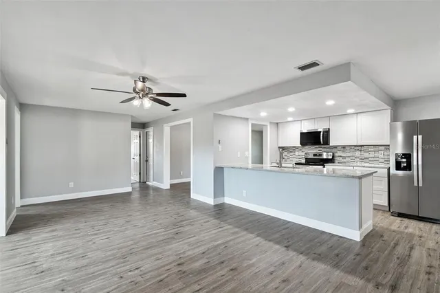 an empty room with wooden floor and a ceiling fan