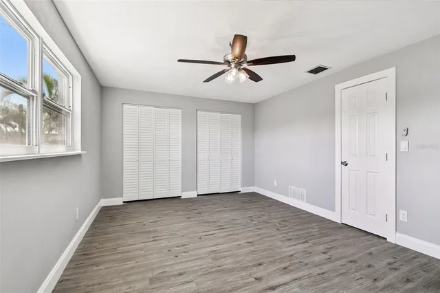 a view of a room with wooden floor and a ceiling fan