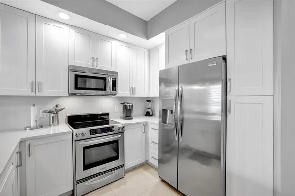 a kitchen with refrigerator a microwave a stove and cabinets