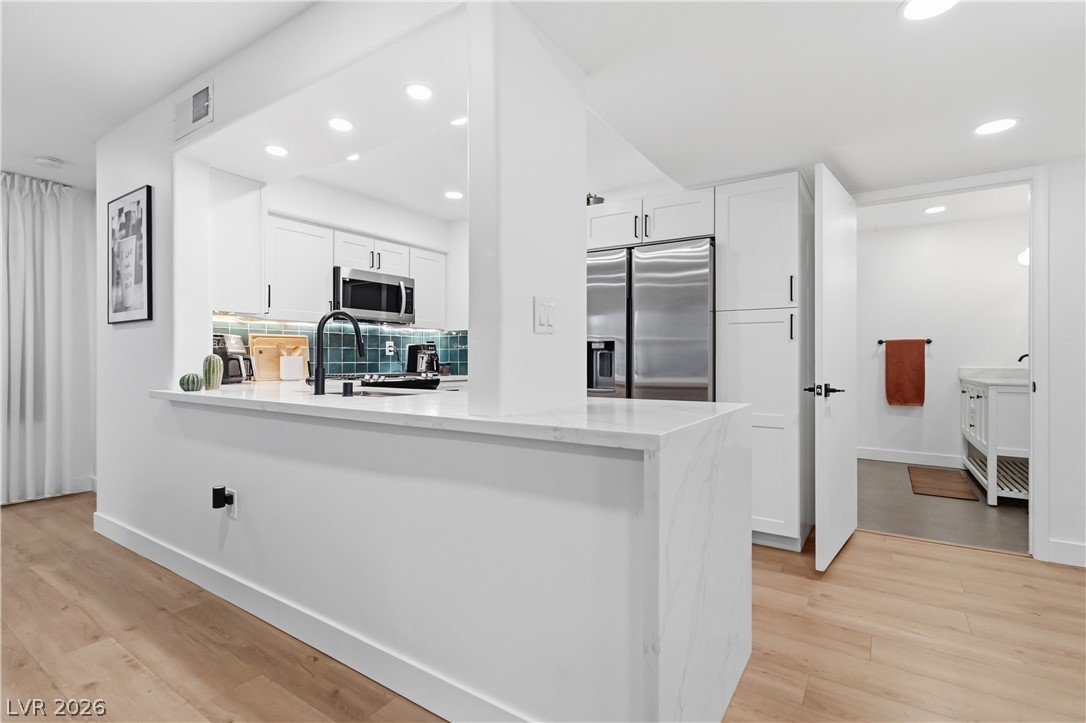 7950 West Flamingo Road, Unit 1180 Las Vegas, NV 89147 - Photo 11 of 26 A contemporary kitchen features bright white cabinetry, stainless steel appliances, and sleek countertops, blending style with utility.