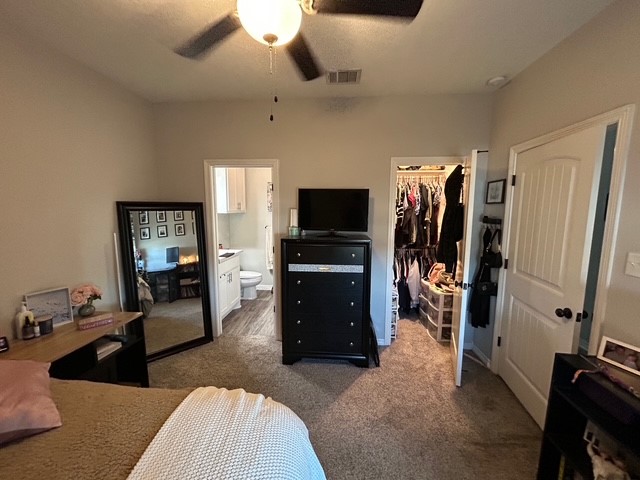 6942 Halter Loop College Station, TX 77845 - Photo 15 of 28 Bedroom with dark colored carpet, a walk in closet, ceiling fan, and ensuite bathroom