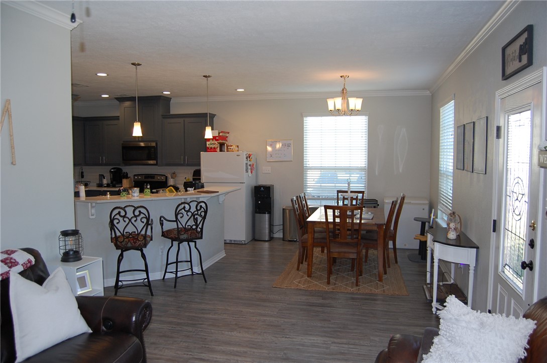 6942 Halter Loop College Station, TX 77845 - Photo 4 of 28 Dining space with crown molding, dark wood-style floors, a chandelier, and recessed lighting