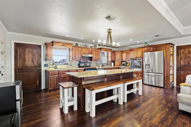 a kitchen with stainless steel appliances granite countertop a refrigerator a stove and a wooden floors