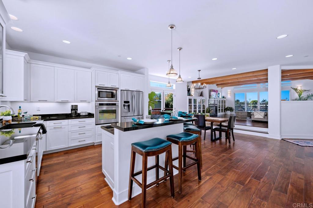 647 Arden Drive Encinitas, CA 92024 - Photo 8 of 36 a kitchen with stainless steel appliances kitchen island granite countertop a stove top oven a sink a dining table and chairs with wooden floor