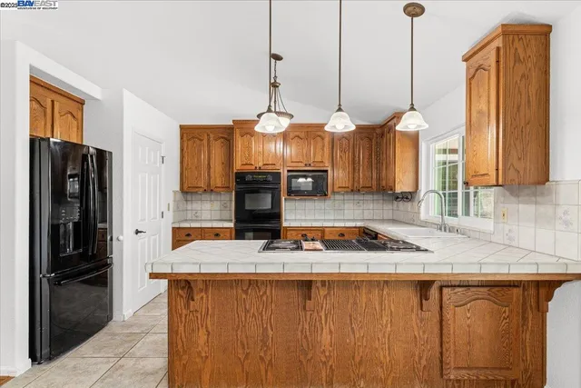 a kitchen with stainless steel appliances granite countertop a stove a sink dishwasher and a refrigerator with wooden cabinets