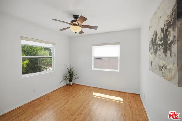 a view of empty room with wooden floor and fan
