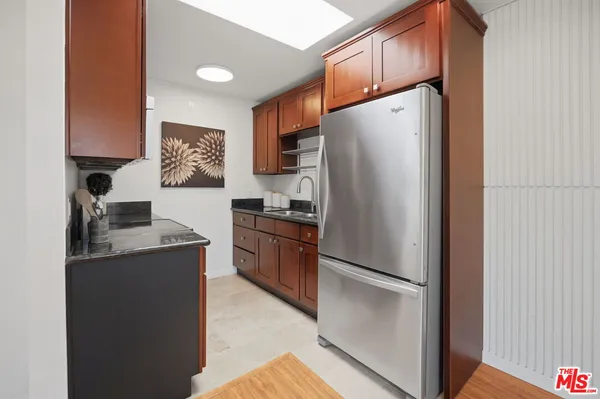 a kitchen with stainless steel appliances granite countertop a refrigerator a stove and a sink with wooden floor