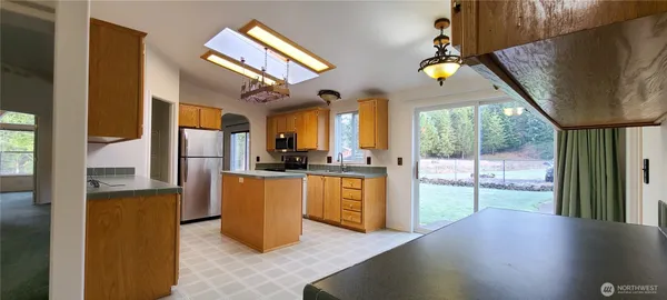 a kitchen with stainless steel appliances granite countertop a sink a stove cabinets and a dining table