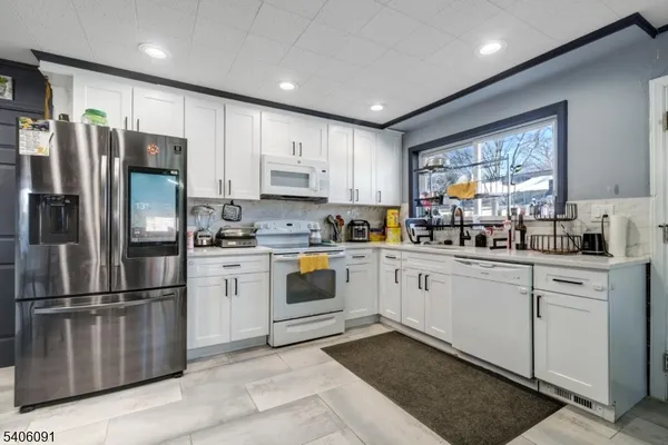 a kitchen with white cabinets stainless steel appliances and window