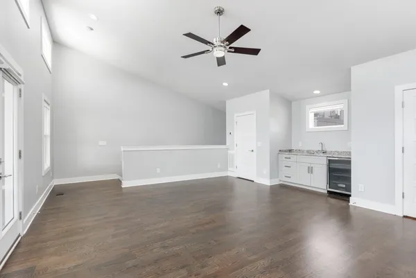 a view of an empty room with a ceiling fan and wooden floor