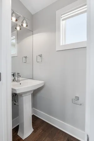 a bathroom with a sink a mirror and wooden floor