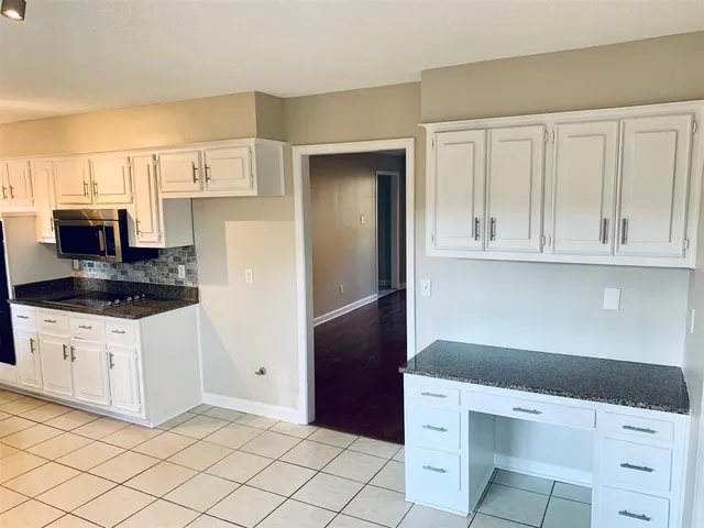 a kitchen with granite countertop white cabinets and white appliances