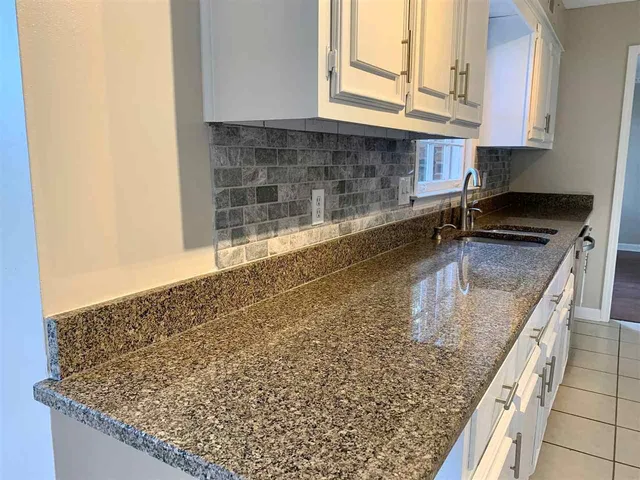 a kitchen with granite countertop a sink a stove and cabinets