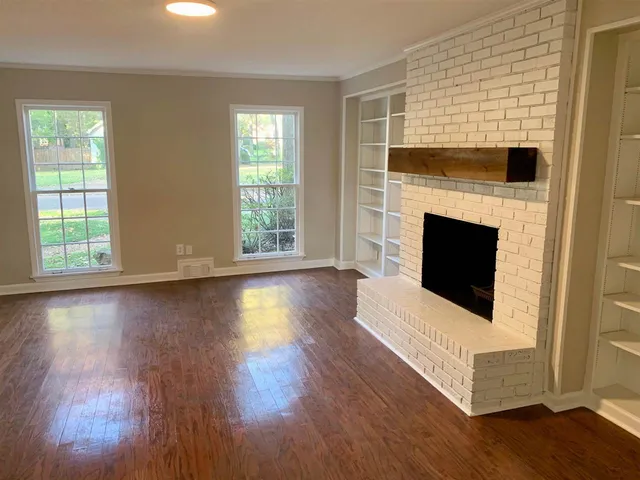 a view of a livingroom with wooden floor and a fireplace
