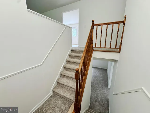 a view of staircase with wooden floor and white walls