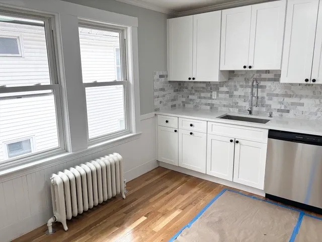 a kitchen with granite countertop white cabinets sink and window