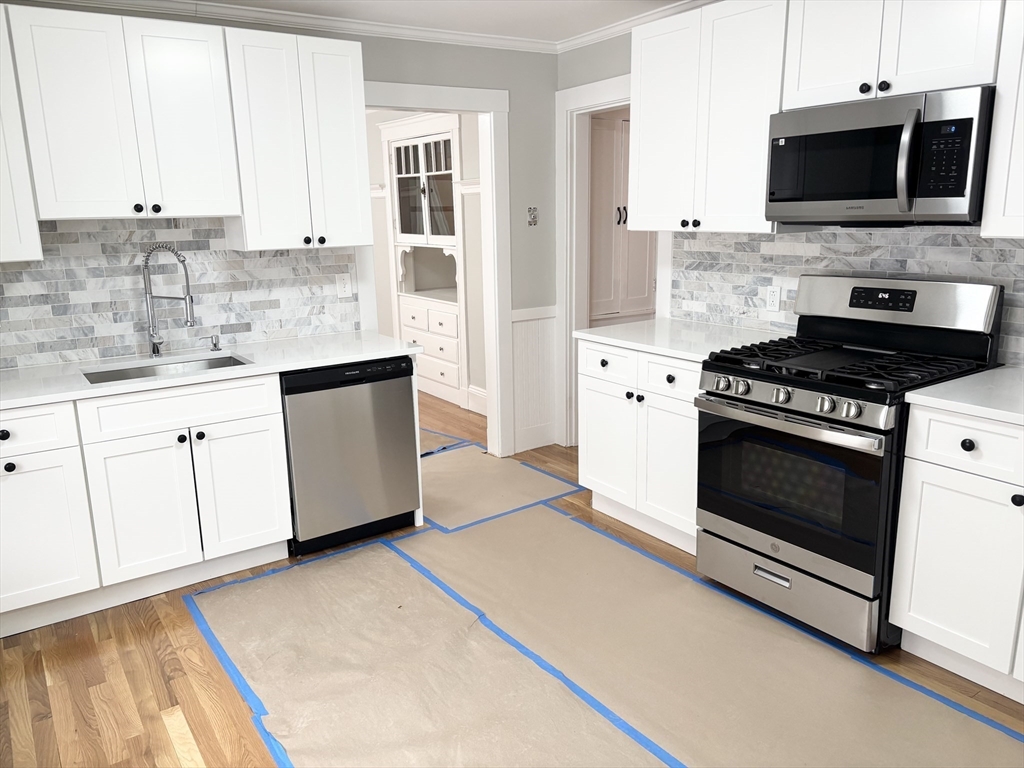 73 Dent Street, Unit 2 Boston, MA 02132 - Photo 8 of 41 a kitchen with stainless steel appliances a stove a microwave a sink and cabinets
